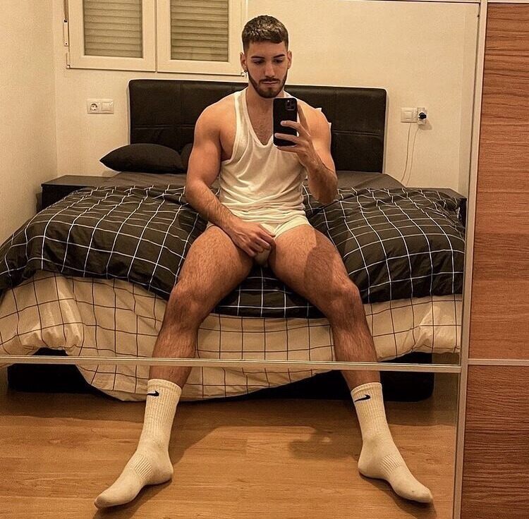 His sitting on the edge of his neatly made bed selfie…