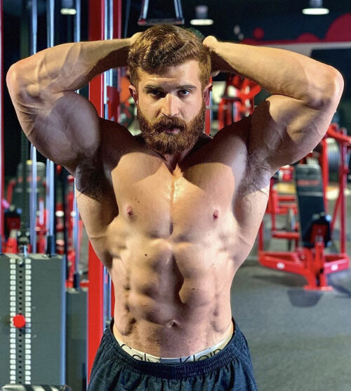 Big muscle posing in front of the equipment.