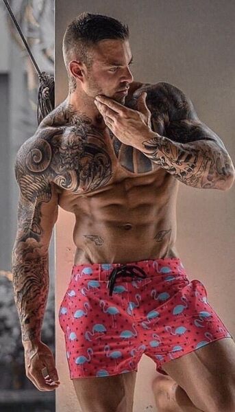 Inked tough dude wearing pinkish flamingo shorts